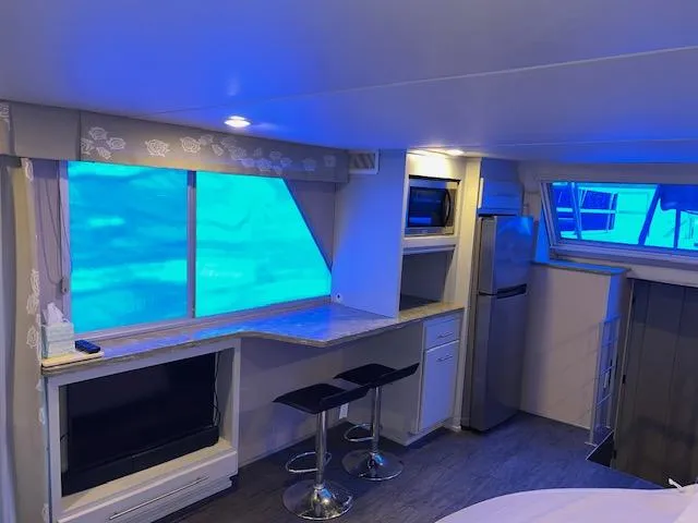 Slide: The Image of Modern kitchen interior with blue lighting, featuring bar stools, counter, and stainless steel appliances. - 33