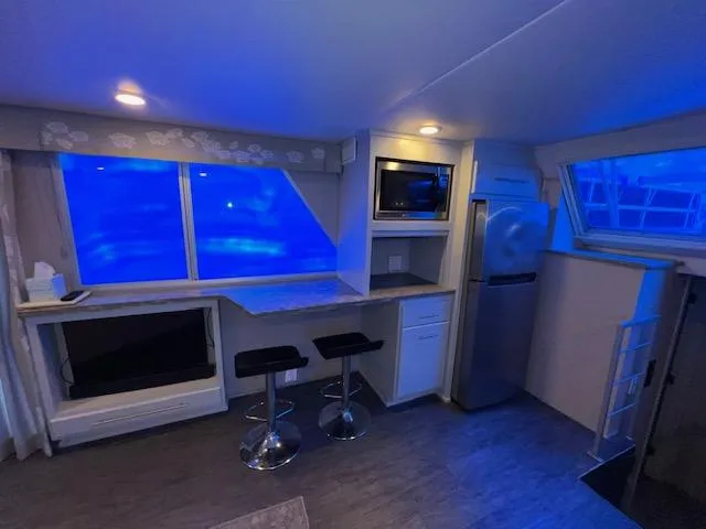 Slide: The Image of Modern kitchen interior with blue lighting, featuring bar stools, counter, microwave, and refrigerator. - 34