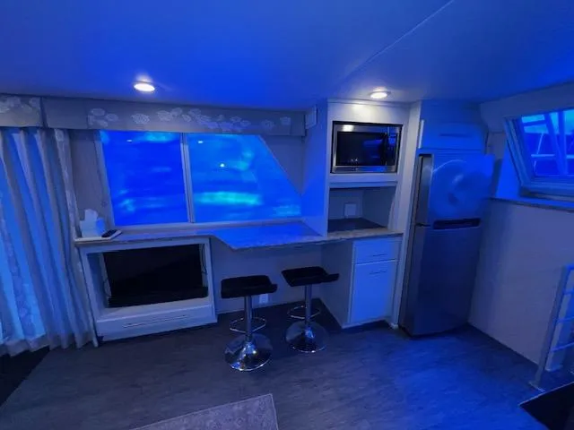 Slide: The Image of Modern kitchen interior with blue lighting, featuring bar stools, a microwave, and a refrigerator. - 35