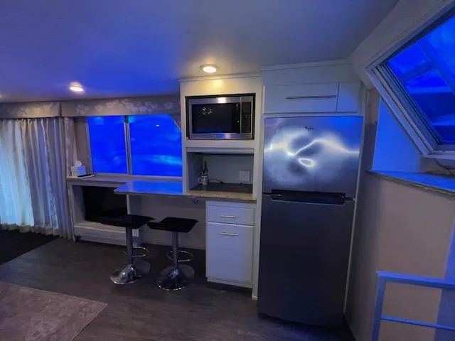 Slide: The Image of Modern kitchen with blue lighting, featuring a 1977 Gibson Standard model, bar stools, and stainless steel appliances. - 36