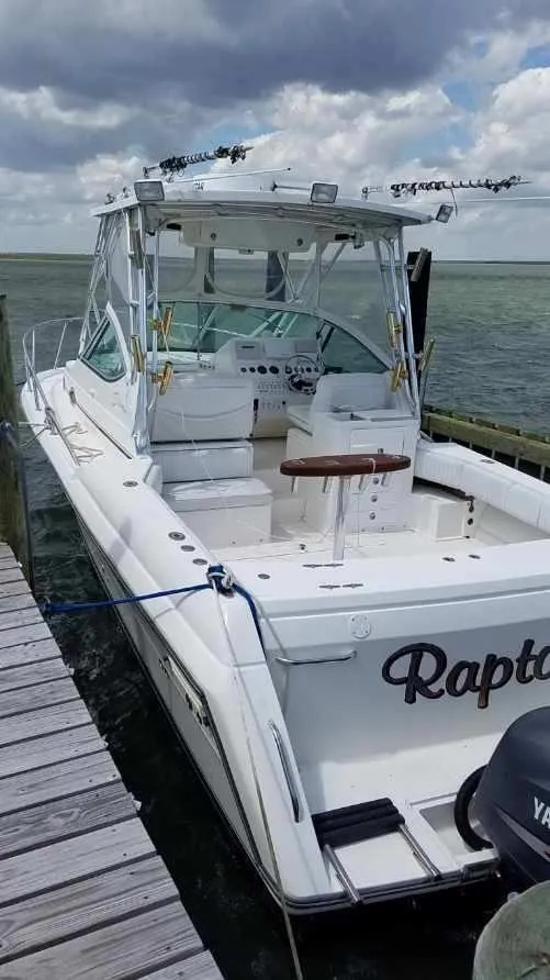 Slide: The Image of 2004 Stamas 310 Express boat docked by the water under cloudy skies. - 1