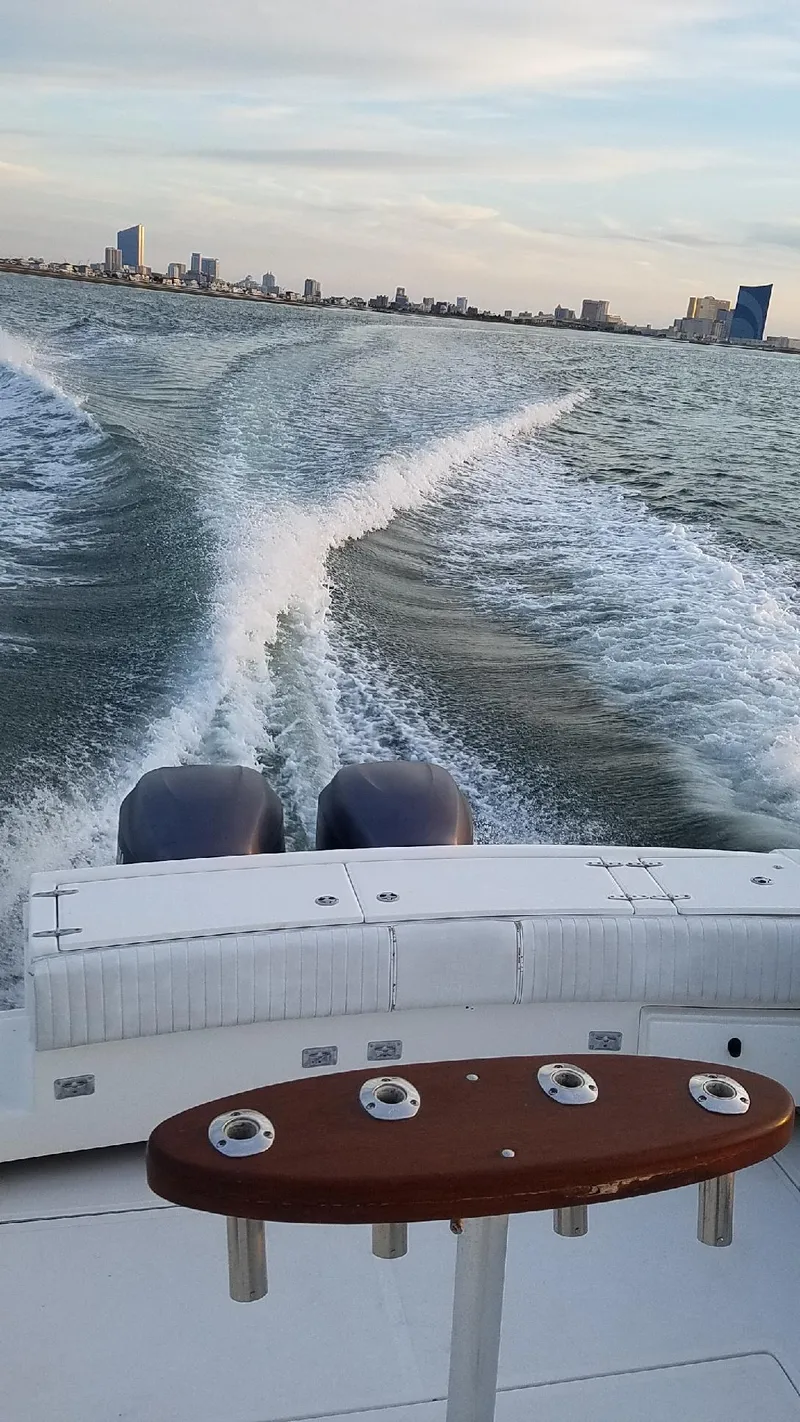 Slide: The Image of 2004 Stamas 310 Express boat cruising on open water with city skyline in background. - 3