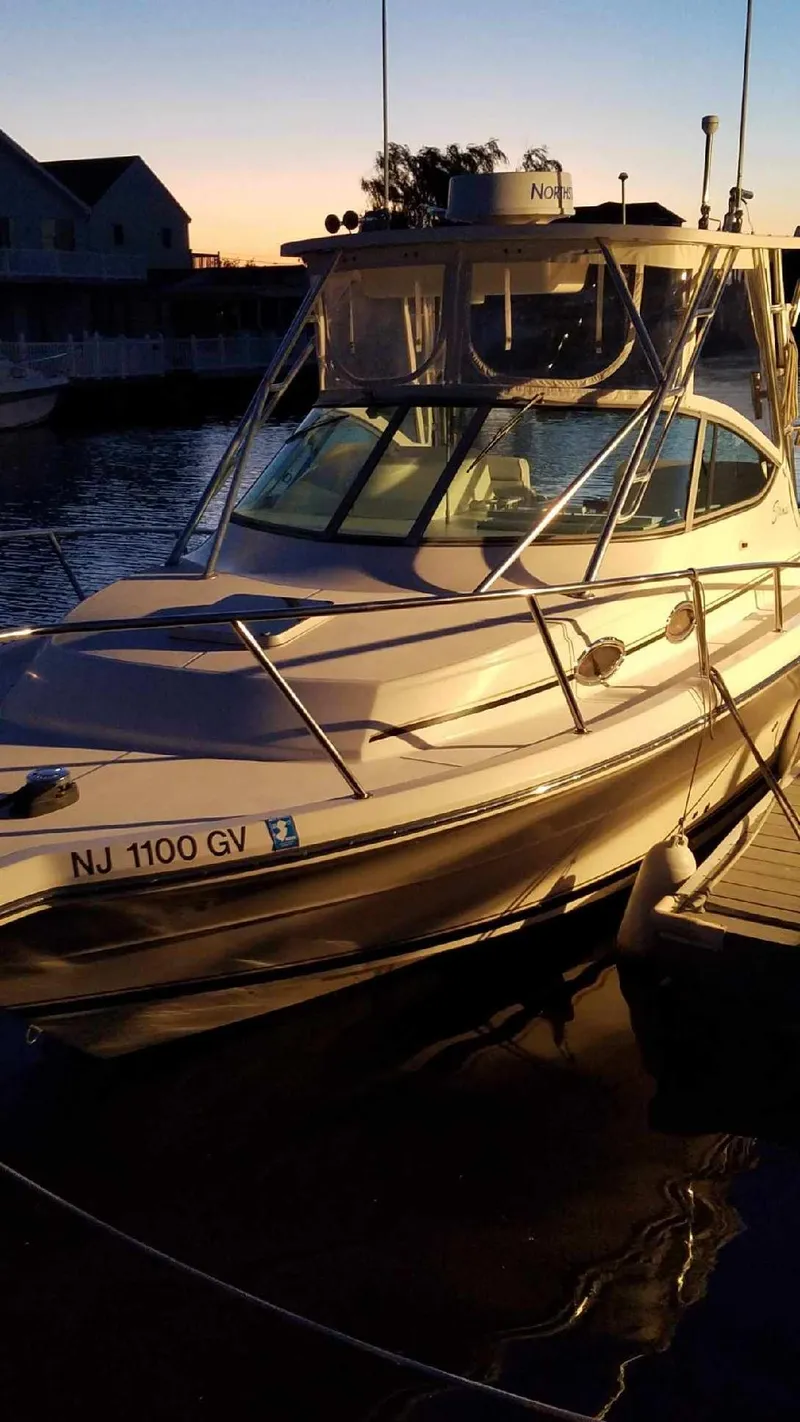 Slide: The Image of 2004 Stamas 310 Express boat docked at sunset, featuring sleek design and spacious cabin. - 5