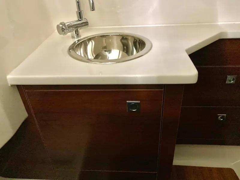 Slide: The Image of 2020 Chaparral 280 OSX boat interior with sleek sink and wooden cabinetry. - 16