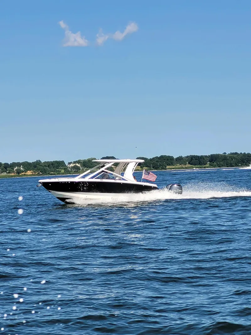 Slide: The Image of 2020 Chaparral 280 OSX boat cruising on a sunny lake with American flag. - 3