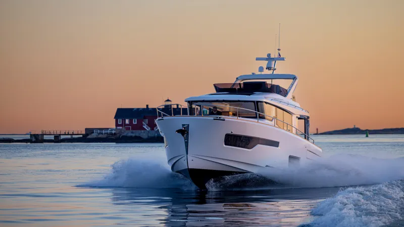 Slide: The Image of Nimbus 495 Flybridge 2025 yacht cruising at sunset near coastal house. - 28