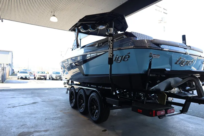 Slide: The Image of 2025 Tigé 24RZX boat on trailer in a covered area, rear view. - 11
