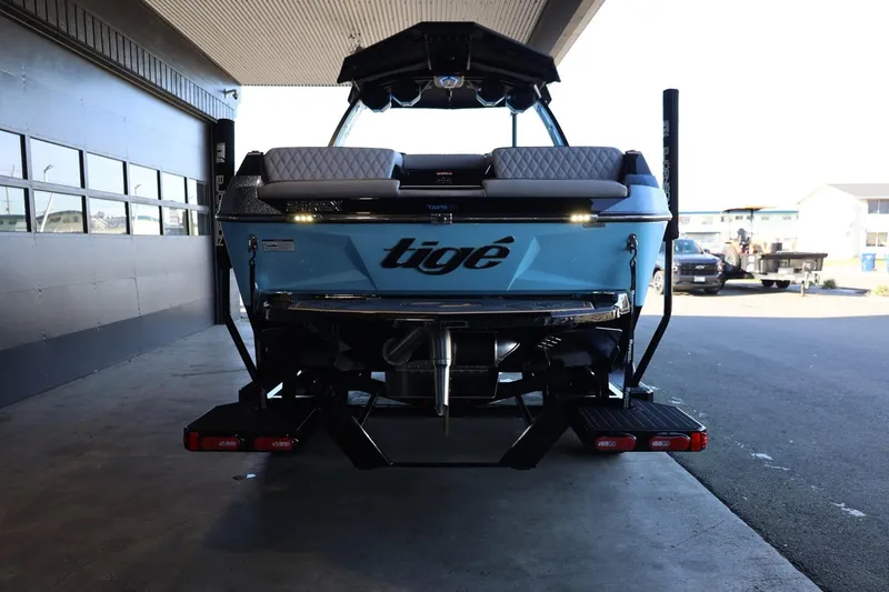 Slide: The Image of 2025 Tigé 24RZX boat, rear view, parked indoors, showcasing sleek design and branding. - 12