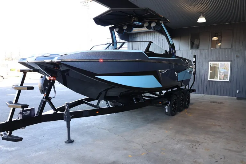 Slide: The Image of 2025 Tigé 24RZX boat on trailer, black and blue design, parked indoors. - 7