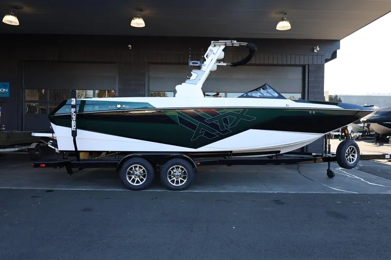 The Image of 2025 ATX Surf Boats 24 Type-S on trailer, sleek design, parked under shelter. - 1