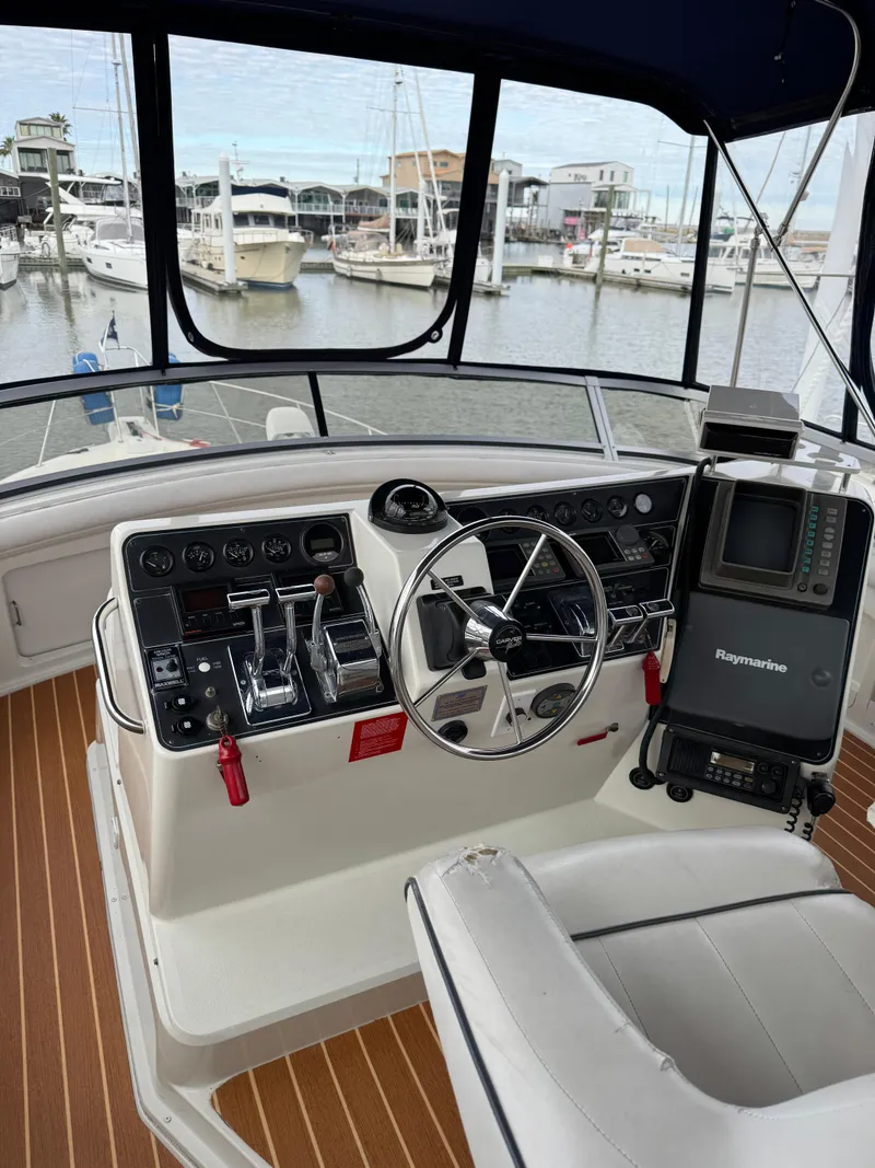 Slide: The Image of 1995 Carver 440 Aft Cabin Motor Yacht helm with navigation equipment and marina view. - 12