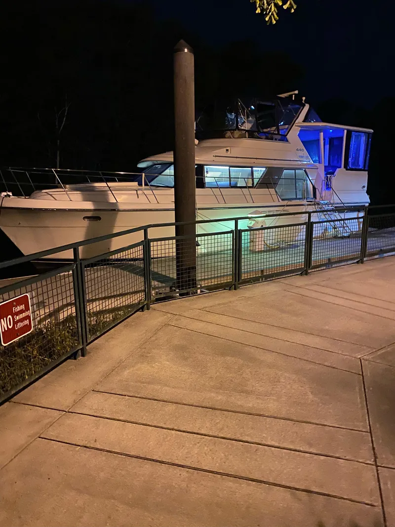 Slide: The Image of 1995 Carver 440 Aft Cabin Motor Yacht docked at night with blue lighting. - 14