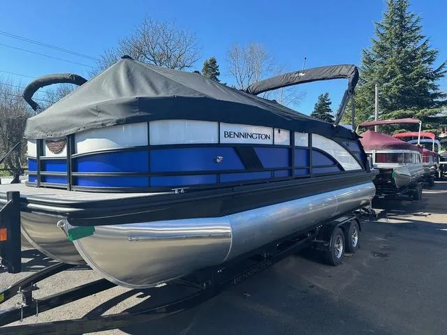 Slide: The Image of 2025 Bennington M Swingback 22 MSB pontoon boat with cover in a warehouse setting. - 1