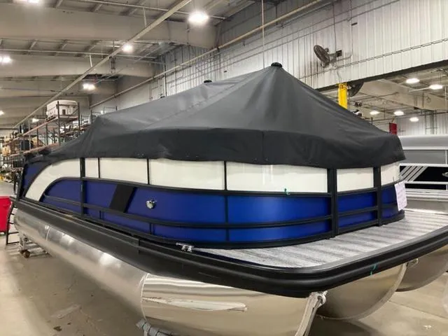 Slide: The Image of 2025 Bennington M Swingback 22 MSB pontoon boat with cover in a warehouse setting. - 3