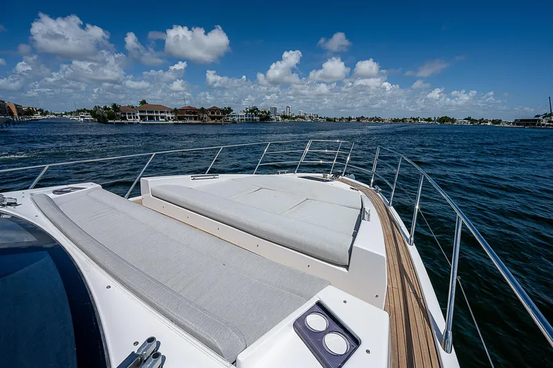 Slide: The Image of 2022 Azimut S6 yacht deck with sunbed, overlooking serene blue waters and distant shoreline. - 12