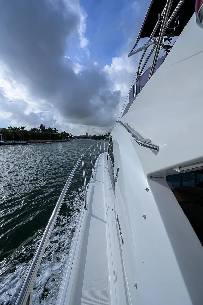 Slide: The Image of 2017 Beneteau Gran Turismo 49 yacht cruising on a scenic waterway under a cloudy sky. - 16