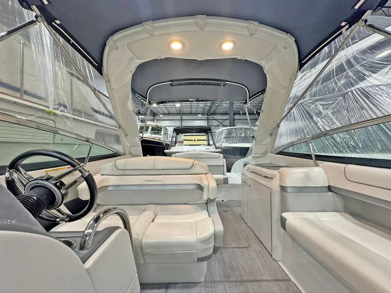 Slide: The Image of 2013 Formula 290 Bowrider interior with plush seating and modern helm in a covered setting. - 38