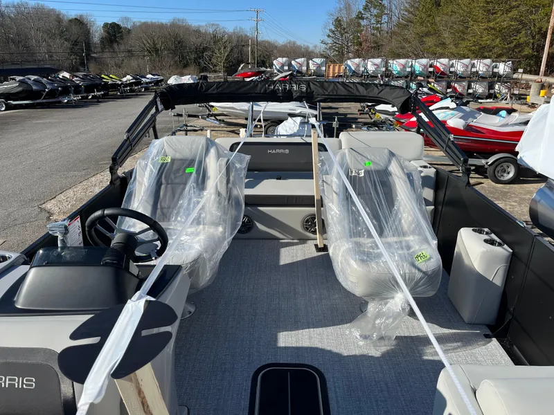 Slide: The Image of 2025 Harris Cruiser 230 boat interior with covered seats, steering wheel, and outdoor setting. - 7