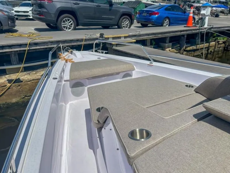 Slide: The Image of 2024 Axopar 45 XC Cross Cabin boat with cushioned seating, docked near vehicles. - 7