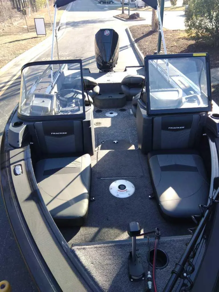 Slide: The Image of 2025 Tracker Targa V-18 Combo boat interior with seating and windshield, parked outdoors. - 2