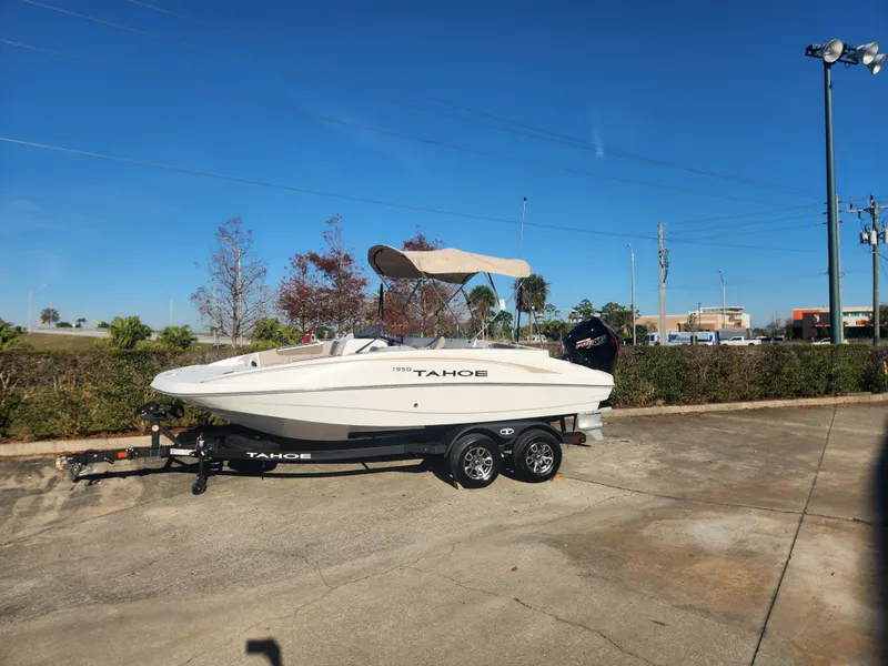 The Image of 2025 Tahoe 1950 boat on trailer, parked outdoors under clear blue sky. - 0