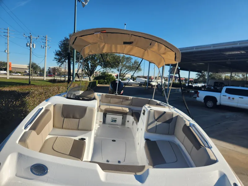 Slide: The Image of 2025 Tahoe 1950 boat with beige seating and canopy, parked outdoors. - 4