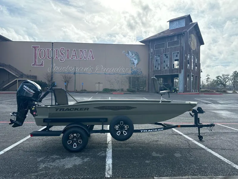Slide: The Image of 2025 Tracker Grizzly 1650 T Prairie Wings Edition boat in parking lot, Louisiana Sportsman's Paradise backdrop. - 2