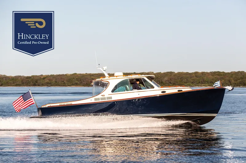 The Image of 2022 Hinckley Picnic Boat 34 S cruising on water, certified pre-owned, with American flag. - 0