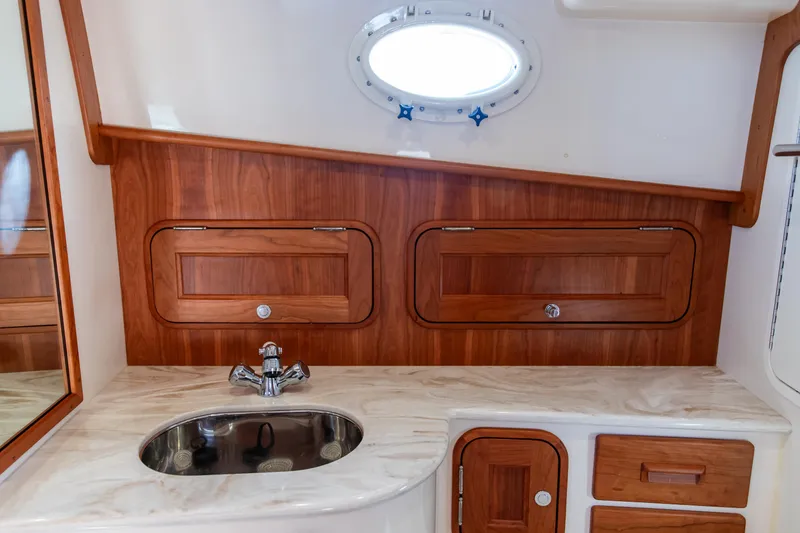 Slide: The Image of 2022 Hinckley Picnic Boat 34 S interior cabin with wood paneling and blue cushions. - 22
