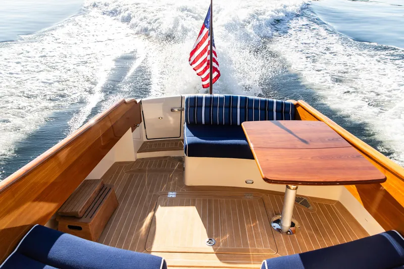 Slide: The Image of 2022 Hinckley Picnic Boat 34 S cruising on a serene lake with American flag. - 6