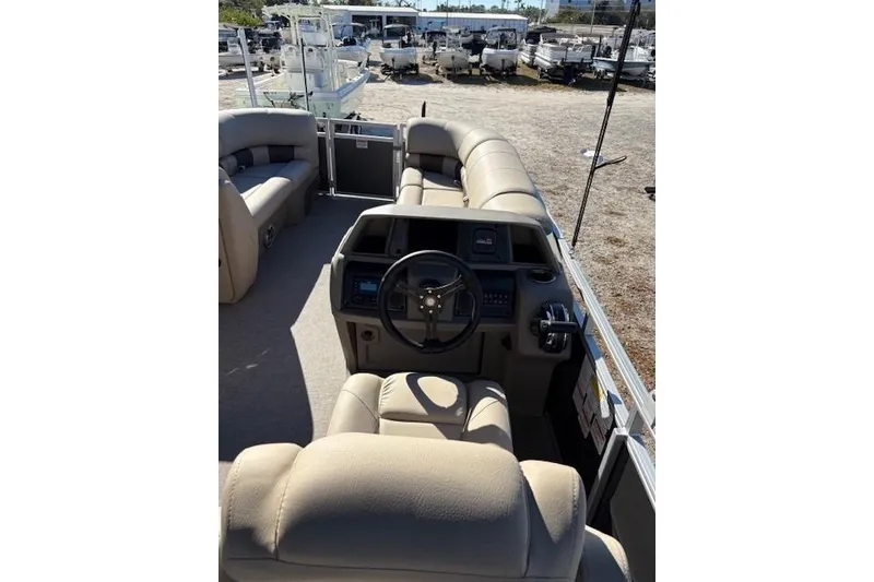 Slide: The Image of 2025 Sun Tracker Party Barge 20 DLX interior with beige seating and steering console. - 2