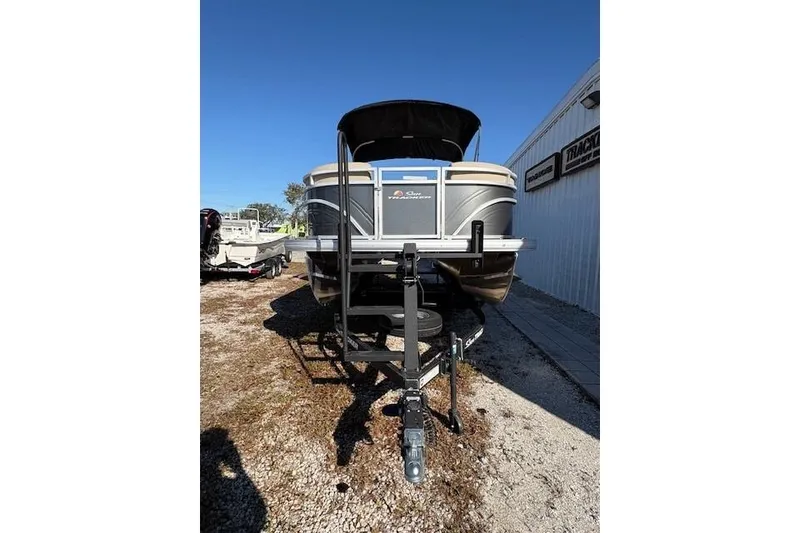 Slide: The Image of 2025 Sun Tracker Party Barge 20 DLX pontoon boat on trailer, parked outdoors. - 4