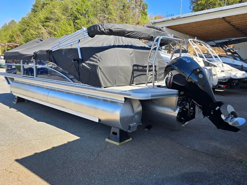 Slide: The Image of 2025 Harris Cruiser 230 pontoon boat with outboard motor, parked outdoors. - 2