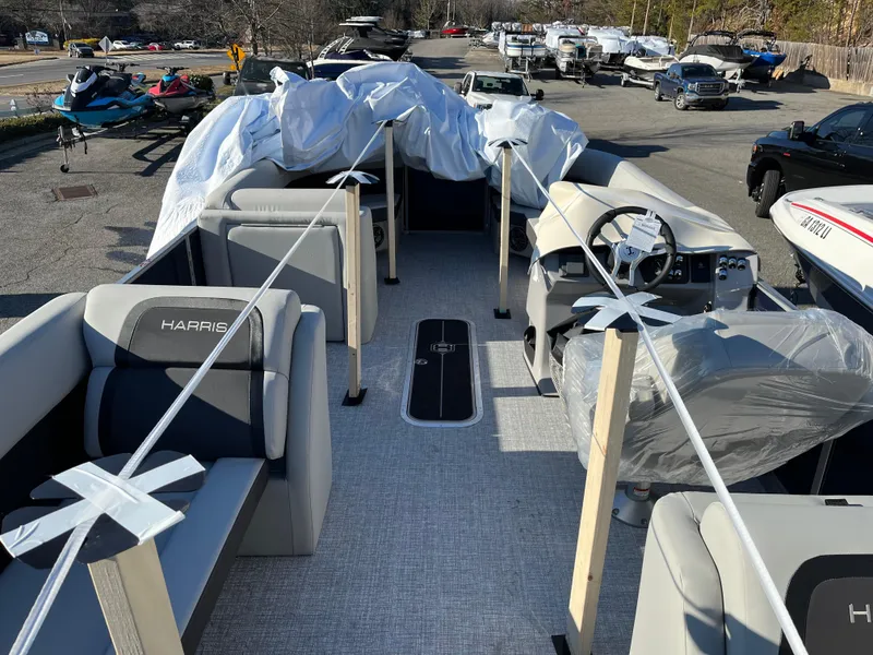 Slide: The Image of 2025 Harris Cruiser 230 pontoon boat interior with protective covers, parked outdoors. - 7