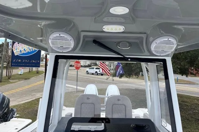 Slide: The Image of 2024 Sea Pro 262 Deluxe CC boat interior with speakers and seating, parked near a road. - 13