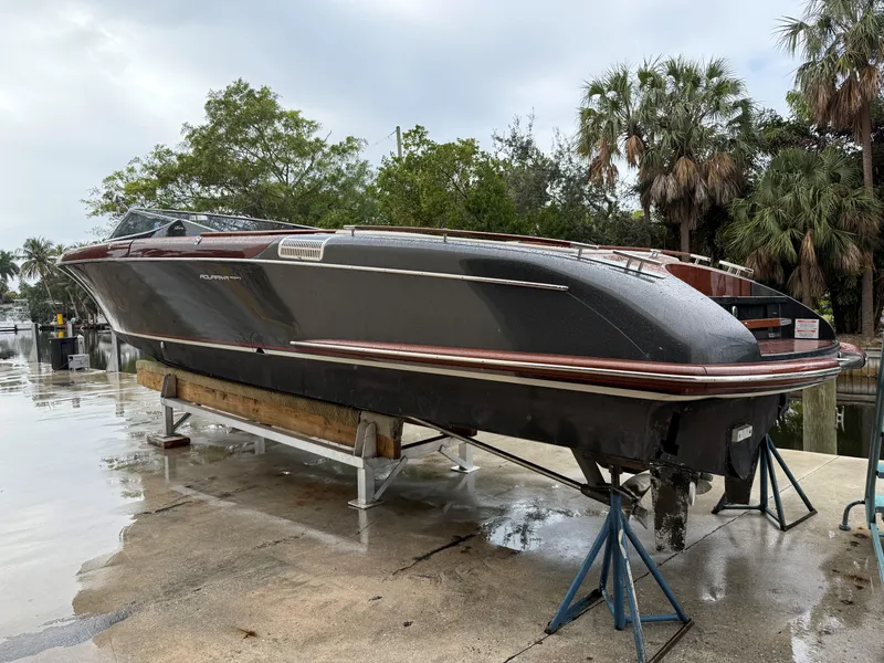 Slide: The Image of 2016 Riva Aquariva Super boat on dry dock, surrounded by trees and wet pavement. - 2