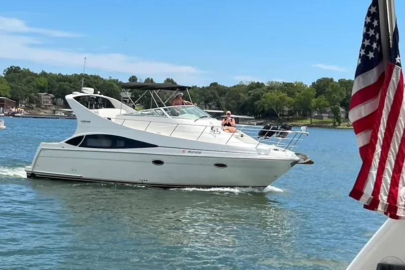 Slide: The Image of 2005 Carver 36 Mariner yacht cruising on a sunny lake with American flag. - 16