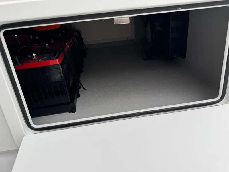 Slide: The Image of Storage compartment of 2025 Shallow Sport 24 Modified V boat, featuring battery setup. - 26