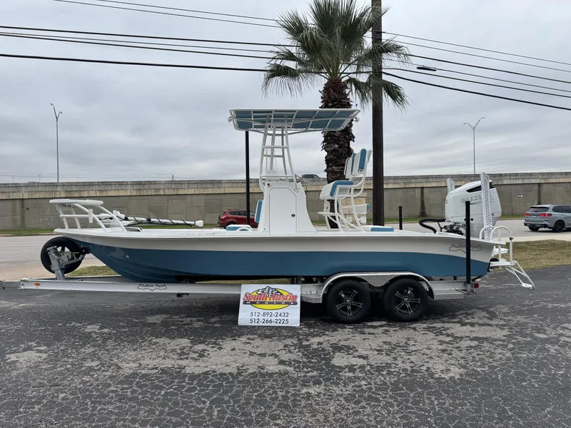 Slide: The Image of 2025 Shallow Sport 24 Modified V boat on trailer, parked outdoors near palm tree. - 38