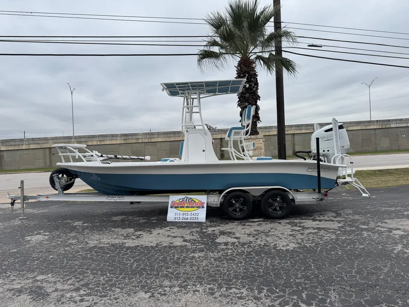 Slide: The Image of 2025 Shallow Sport 24 Modified V boat on trailer, parked near palm tree. - 43