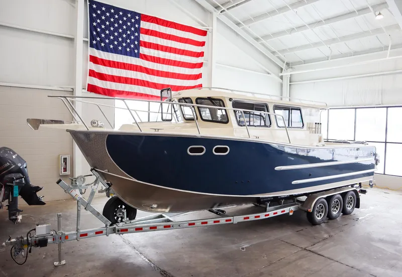 Slide: The Image of 2025 Hewescraft 290 Adventure ET HT boat on trailer in warehouse with American flag. - 1