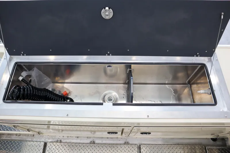 Slide: The Image of 2025 Hewescraft 290 Adventure ET HT boat storage compartment, open lid, stainless steel interior. - 11