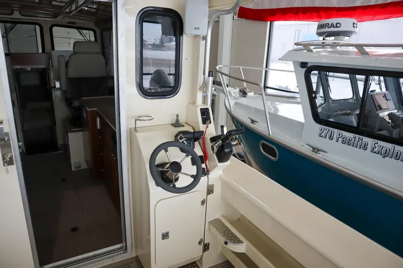 Slide: The Image of 2025 Hewescraft 290 Adventure ET HT boat interior with steering wheel and cabin view. - 14