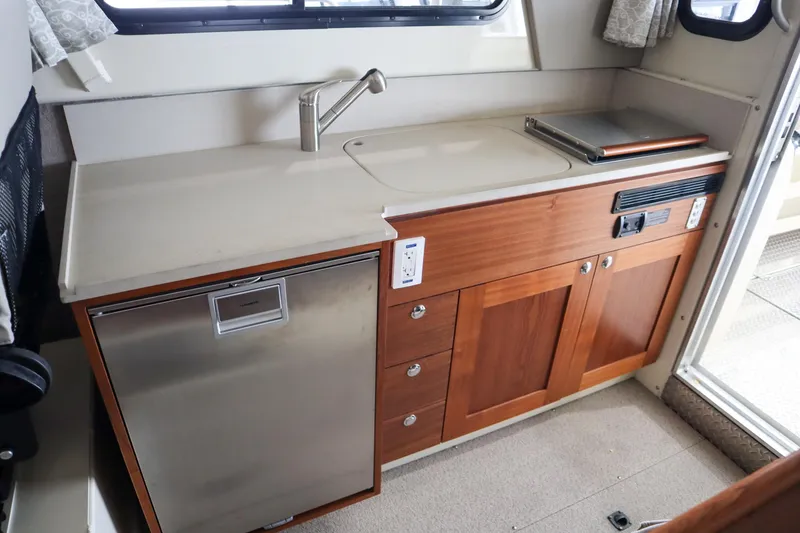 Slide: The Image of 2025 Hewescraft 290 Adventure ET HT interior kitchen with sink, fridge, and wooden cabinetry. - 19