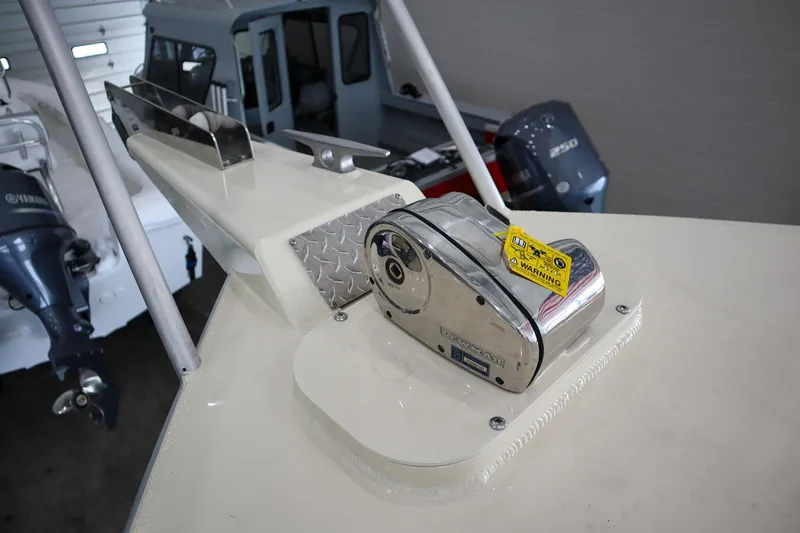 Slide: The Image of 2025 Hewescraft 290 Adventure ET HT boat detail, featuring anchor winch and motor in a showroom. - 43