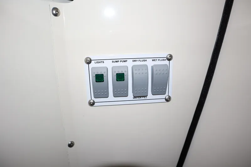 Slide: The Image of Control panel with switches for lights, sump pump, dry flush, and wet flush on 2025 Hewescraft 290 Adventure ET HT. - 46