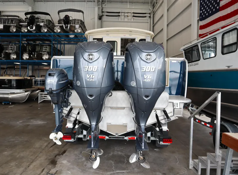 Slide: The Image of 2025 Hewescraft 290 Adventure ET HT with twin 300 V6 outboard engines in a boatyard. - 6
