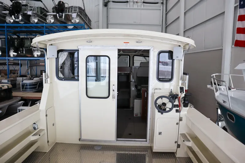 Slide: The Image of 2025 Hewescraft 290 Adventure ET HT boat interior, featuring helm and sliding door in a showroom. - 7