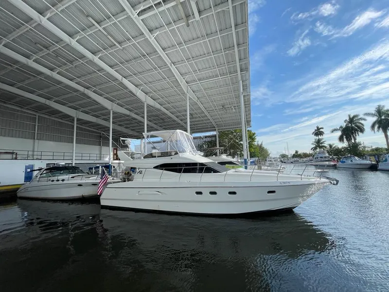 Slide: The Image of Azimut 43 yacht from 1997 docked under a covered marina with palm trees nearby. - 16