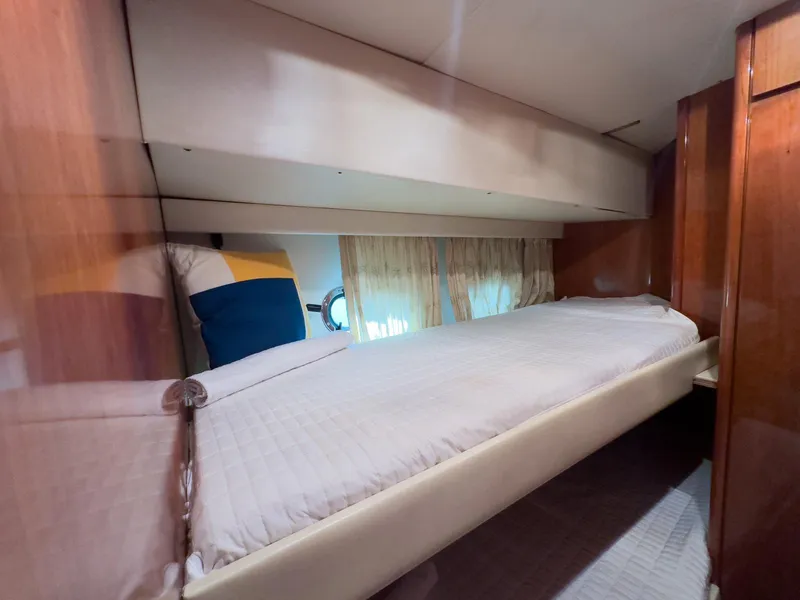 Slide: The Image of 1997 Azimut 43 yacht cabin with single bed, wooden paneling, and porthole window. - 33